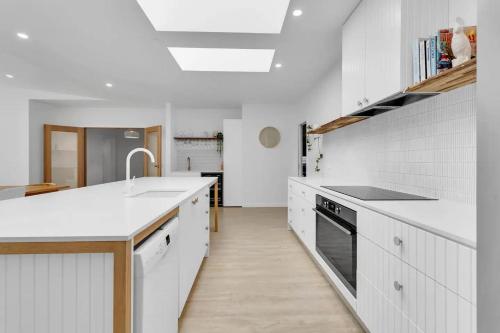 a white kitchen with white cabinets and a sink at The Family Beachside Escape by Ready Set Stay - HOUSE in Rosebud