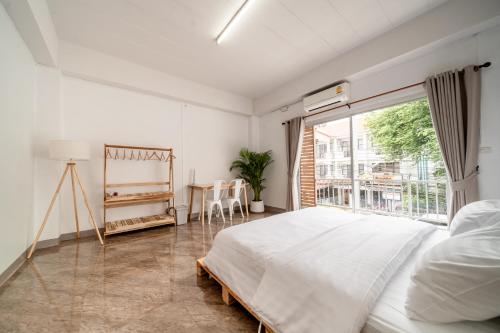 Un dormitorio con una cama y una ventana grande. en Socialer Coliving & Coworking Space, en Chiang Mai