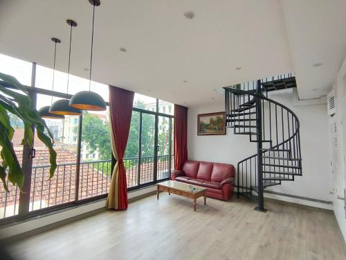 a living room with a red couch and a spiral staircase at Homestay Torna A Casa không thang máy in Hanoi