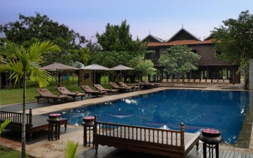 a pool at a resort with chairs and umbrellas at Mane Hariharalaya in Siem Reap