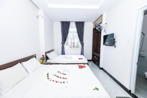 a white bedroom with two beds and a window at Ciao Quy Nhơn in Quy Nhon