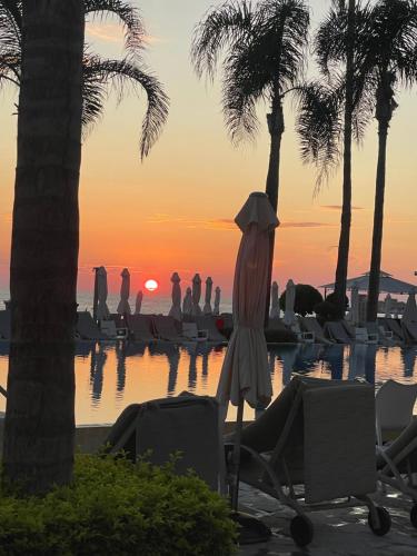 ein Resortpool mit Palmen und Sonnenuntergang in der Unterkunft Cozy Paphos Apartment in Paphos City
