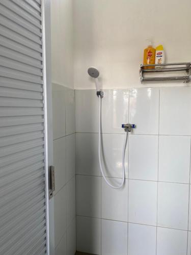 a white tiled shower with a shower head in a bathroom at Banana Homestay in Banyuwangi