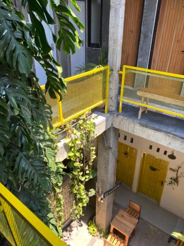 a balcony with a yellow bench and a wooden table at Banana Homestay in Banyuwangi