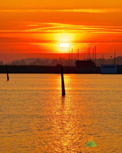 a sunset over a body of water with boats at Villa Wiegand - a room with a view in Holbæk