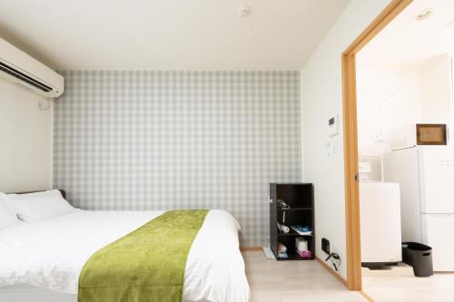 a bedroom with a bed and a tiled wall at 駅近徒歩3分。生活に便利なアパート。長期滞在にもオススメ in Daitō