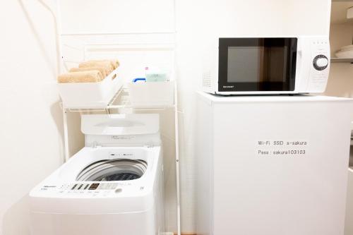 a washer and dryer with a microwave on top of a refrigerator at 駅近徒歩3分。生活に便利なアパート。長期滞在にもオススメ in Daitō