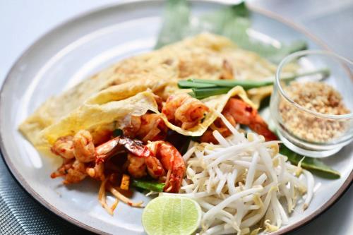 a white plate of food with shrimp and rice at The Pago Design Hotel Phuket-SHA Plus in Phuket Town