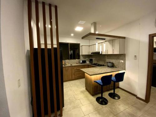 a kitchen with two blue stools and a counter at Hermoso departamento con piscina en la playa in Playas