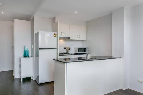uma cozinha branca com um frigorífico e um lavatório em WILL1 - Stylish 2-Bed 2-Bath Oasis in Crows Nest Village em Sydney