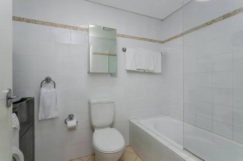 a white bathroom with a toilet and a bath tub at WILL1 - Stylish 2-Bed 2-Bath Oasis in Crows Nest Village in Sydney