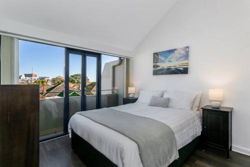 um quarto com uma cama grande e uma janela grande em WILL1 - Stylish 2-Bed 2-Bath Oasis in Crows Nest Village em Sydney