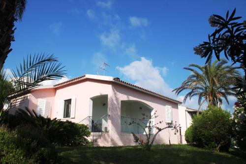 a white house with palm trees in front of it at Villa Diana affitta camere in Stintino