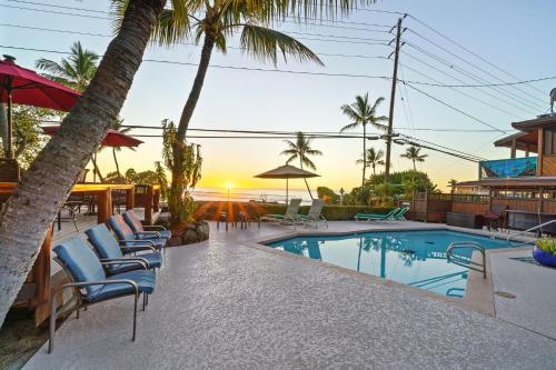 a swimming pool with lounge chairs and a resort at Seaspray Oceanview in Kailua-Kona