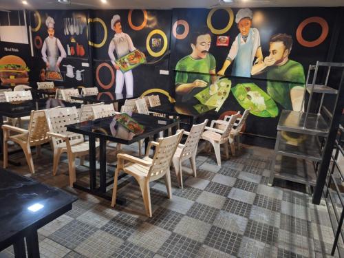 a dining room with tables and chairs and a mural at Hotel B R REGENCY in Trivandrum