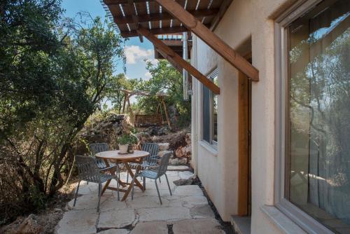 Abirim的住宿－בית האלה Home of Ela，一个带桌椅的庭院和一个窗户。