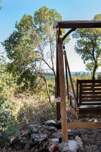 a wooden swing on a hill with trees and rocks at בית האלה Home of Ela in Abirim