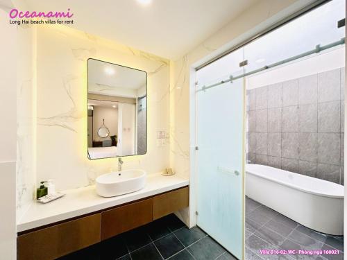 W łazience znajduje się umywalka, wanna i lustro. w obiekcie Villa 1602 Oceanami, Sát biển, Hồ bơi riêng, 837m2 w mieście Long Hai