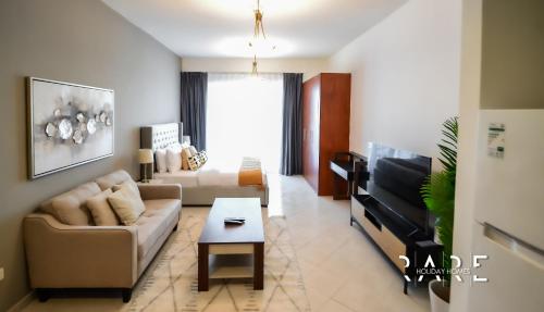 a living room with a couch and a tv at RARE Holiday Homes - Stylish - Near City Centre Mall - Crescent Tower - R1611 - IMPZ in Dubai