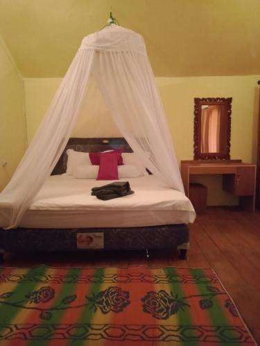 a bedroom with a bed with a mosquito net at Why Not Bar And Bungalows #2 in Pawenang