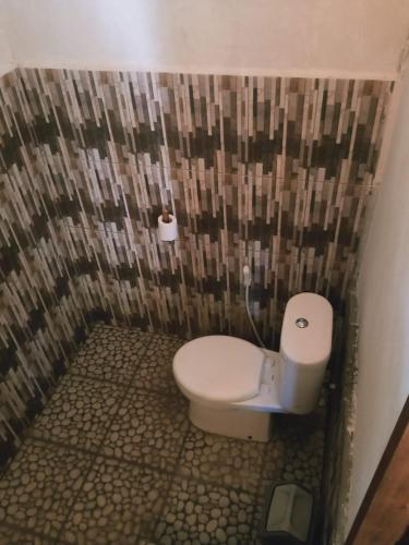 a bathroom with a white toilet in a wall at Why Not Bar And Bungalows #2 in Pawenang