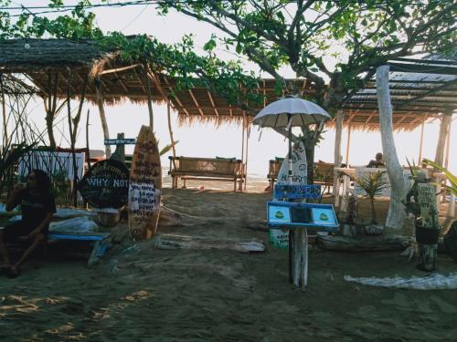 a hut with an umbrella and people sitting under it at Why Not Bar And Bungalows #2 in Pawenang