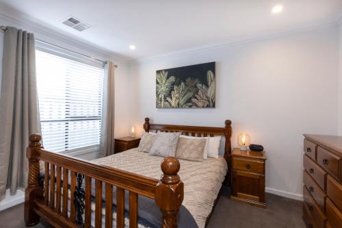 a bedroom with a wooden bed and a window at Cozy Getaway, King Bed with TV, NBN, Netflix, Nespresso in Christies Beach