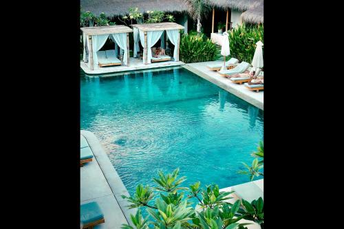 a swimming pool with lounge chairs in a resort at Rascals Hotel - Adults Only in Kuta Lombok