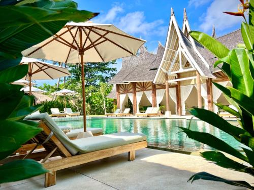 a pool with chairs and umbrellas next to a resort at Rascals Hotel - Adults Only in Kuta Lombok