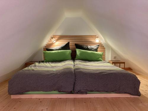 a bed with two green pillows in a attic at In der Wassermühle in Melle