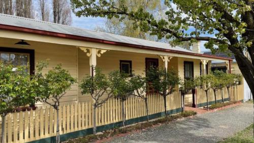 a yellow house with a fence in front of it at Picketts Cottage in Beechworth