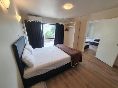 a small bedroom with a bed and a window at Ascot Epsom Motel in Auckland