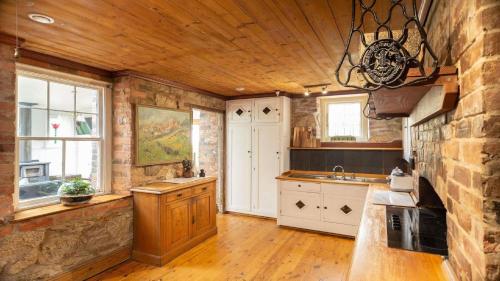 a kitchen with wooden ceilings and a stone wall at Isabellas At Beechworth in Beechworth