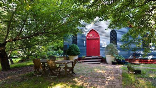 une église avec une porte rouge et une table et des chaises dans l'établissement Blue Gum Church - Artistic Retreat, à Beechworth
