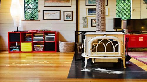 a living room with a fireplace and a red cabinet at Blue Gum Church - Artistic Retreat in Beechworth