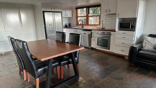 a kitchen with a wooden table and black chairs at Sunset On Ford in Beechworth