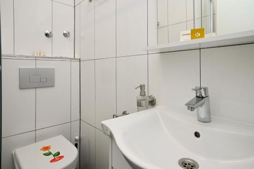 Baño blanco con lavabo y aseo en Ferienwohnung&Aparts By kispet group hotels in Oberhausen, en Oberhausen