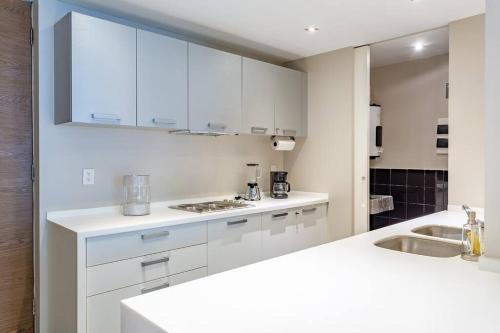 a white kitchen with white cabinets and a sink at Moderno Departamento en Reforma 284 in Mexico City