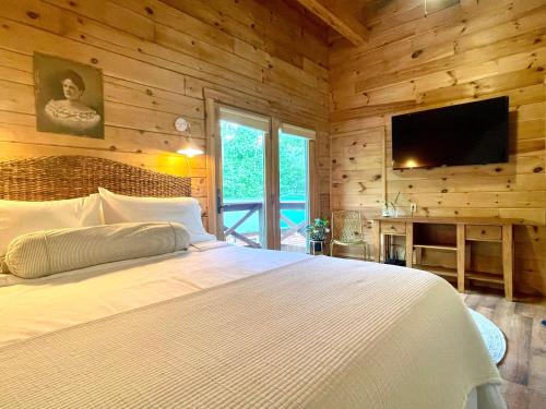 a bedroom with a white bed and a flat screen tv at Mossy Falls Cabin by Leavetown Vacations 