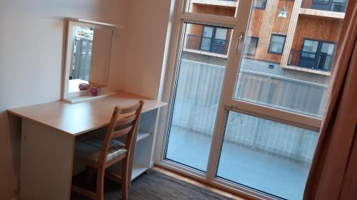 a desk with a chair next to a large window at Stockholm Private Rooms in Shared Lovely, Amazing, Modern Apartment +Garden +BBQ in Stockholm