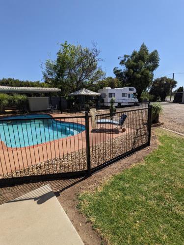a fence around a swimming pool with an rv in the background at Kaputar Motel in Narrabri