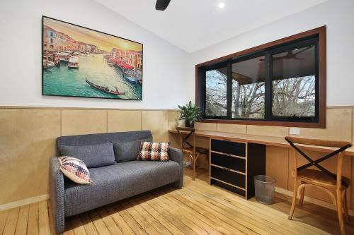 a living room with a couch and a painting on the wall at Millie & Pips Beechworth Bungalow in Beechworth