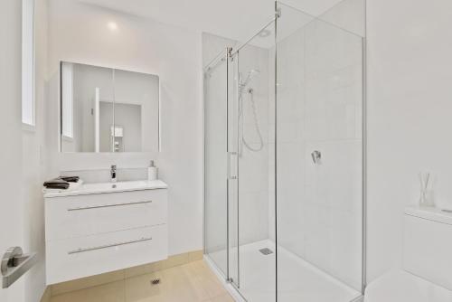 a white bathroom with a sink and a shower at Central City-Urban Oasis 1 bed 1 bath w/sofa bed in Christchurch
