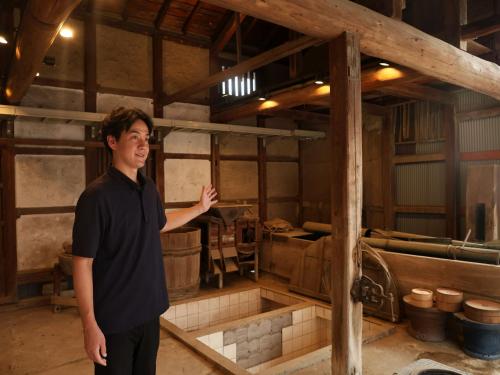 a man standing in a room with a sink at NIPPONIA 田原本 マルト醤油 in Nara