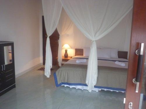 1 dormitorio con 1 cama con dosel en Tambun Sari Beach Homestay en Amed