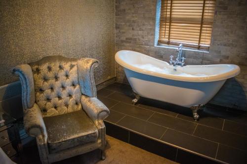 a bathroom with a tub and a chair and a sink at The George Wright Boutique Hotel, Bar & Restaurant in Rotherham