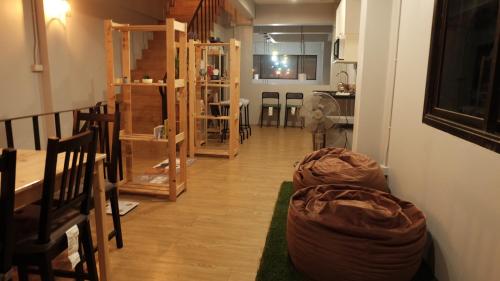 un soggiorno con pavimenti in legno e un corridoio con sedie. di A lazy person hostel a Chumphon