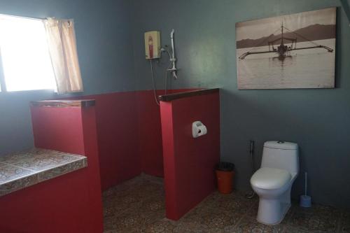 a bathroom with a toilet and a picture of a boat on the wall at Marianita's cottages in Mambajao