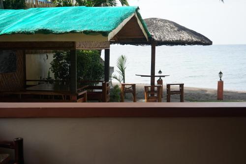 a shack with chairs and a table on the beach at Marianita's cottages in Mambajao