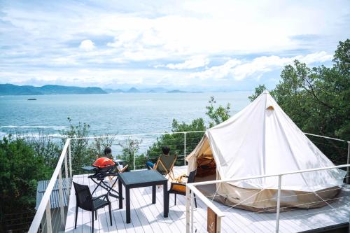 a tent on a deck with a view of the water at てんとうみ 渋川海岸グランピング Tentoumi Shibukawa Beach Glamping in Tamano